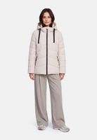 Frau trägt beige Daunenjacke mit Hood, weiten Hosen und Sneakern, steht lässig stehend.