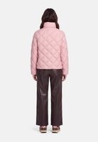 Frau trägt pinken Quilted-Jacket mit dunklen Hosen und Sandalen von hinten.