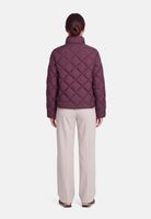 Frau trägt burgunderfarbenen Quilted-Jacket mit hellgrauen Hosen, Rückansicht.