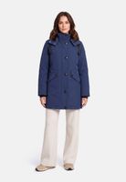 Frau trägt hellblaue Daunenjacke mit Knöpfen, beige Hosen und flache Schuhe.
