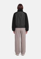 Person von hinten in schwarzem Fleece-Jacken-Set mit grauen, weiten Hosen.