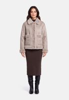 Frau trägt beige gefütterte Jacke mit Puffärmeln, braunen Cordrock und schwarzen Stiefeln.