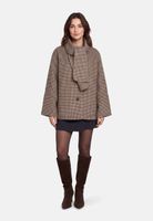 Frau trägt kariertes oversized Sakko, dunkle Shorts, Strumpfhose und braune Kniestrümpfe mit Blockabsatz.