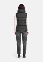 Person trägt grauen Daunenweste über weißem Rollkragenpullover, graue Jeans und schwarze Stilettos.