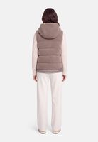 Person trägt beige Daunenweste über hellem Rollkragenpullover und weiten Hosen, von hinten fotografiert.