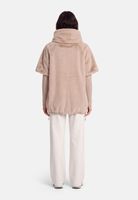 Person trägt beige, flauschigen Hooded-Jackenoverlook mit weißen, weiten Hosen, von hinten.
