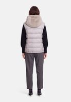 Person trägt graue Puffweste mit Kapuze, schwarze Bluse und graue Anzughose mit schwarzen Pumps.