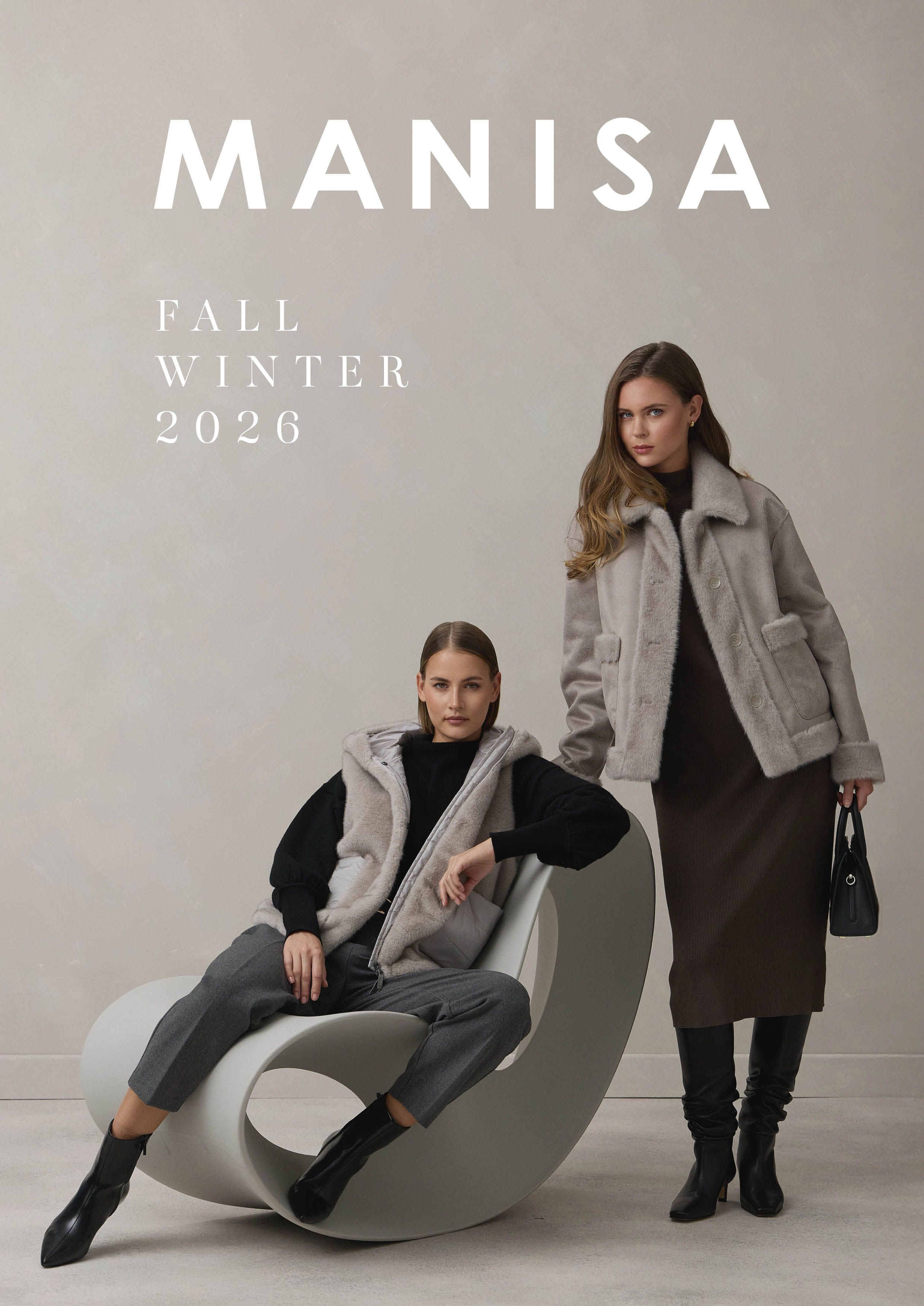 Zwei Frauen im Manisa-Fall-Winter-2026-Look mit stylischen Mänteln und moderner Sitzgelegenheit.
