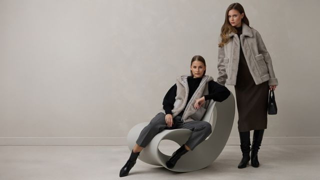 Zwei Personen sitzen lässig auf modernem, weißem Sitzmöbel in stylischer Winterkleidung.