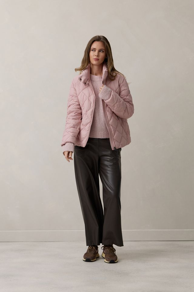 Frau trägt pinken Quilted-Jacket mit Schal, schwarze Hosen und braune Stiefel.